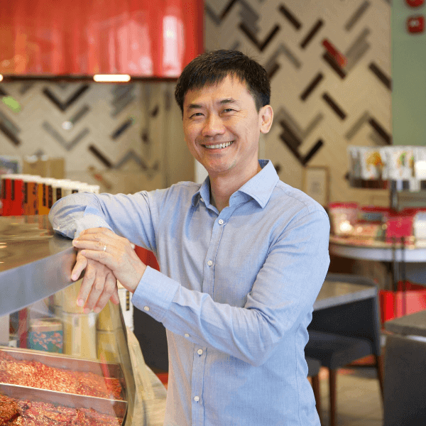 a person in a blue shirt standing in front of a counter with candy jars inside a brightly lit store with red accents and decorative elements on the wall